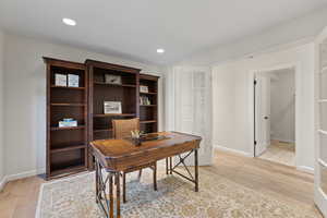 Office with light wood-style flooring and recessed lighting
