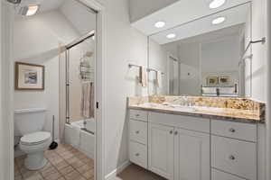 Full bath with vanity, light tile patterned flooring, and bath / shower combo with glass door