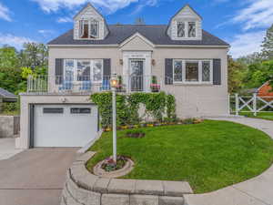 View of front of home with brick siding, a front lawn, driveway, and an attached garage