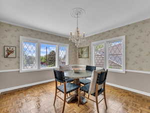 Dining space featuring healthy amount of natural light, a wainscoted wall, a chandelier, and wallpapered walls