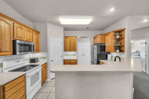 Kitchen with appliances with stainless steel finishes, light countertops, tasteful backsplash, and light tile patterned floors