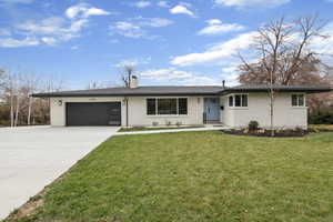 Ranch-style home featuring brick siding, concrete driveway, a garage, a chimney, and a front lawn