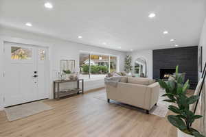 Living area featuring light wood finished floors, a stone fireplace, and recessed lighting