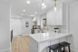 Kitchen with a breakfast bar, light stone counters, tasteful backsplash, a peninsula, and high end stainless steel range oven