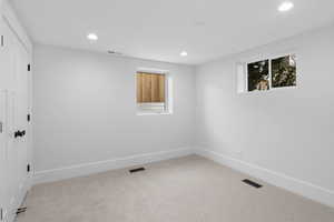 Empty room with light colored carpet and recessed lighting