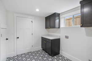 Laundry room featuring washer hookup, cabinet space, light tile patterned floors, and recessed lighting
