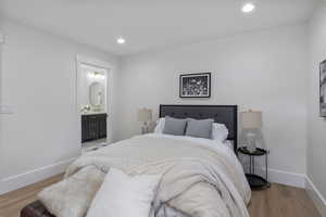 Bedroom with wood finished floors, recessed lighting, and ensuite bath