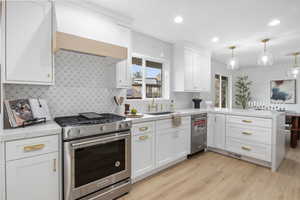 Kitchen featuring stainless steel appliances, a peninsula, light stone counters, white cabinets, and recessed lighting