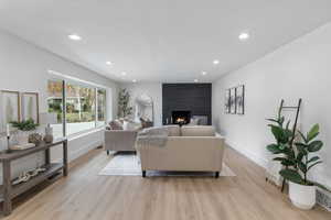 Living room with light wood finished floors, a large fireplace, recessed lighting, a textured ceiling, and arched walkways