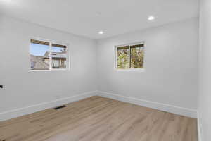 Spare room featuring wood finished floors, plenty of natural light, and recessed lighting