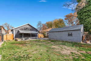 Fenced backyard with a patio area, a gate, and an outbuilding