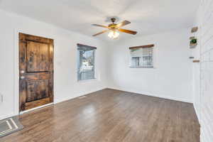 Unfurnished room featuring wood finished floors, ceiling fan, and a textured ceiling