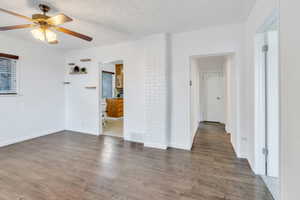 Empty room featuring a textured ceiling, wood finished floors, and a ceiling fan