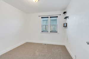 Carpeted empty room featuring baseboards and a textured ceiling