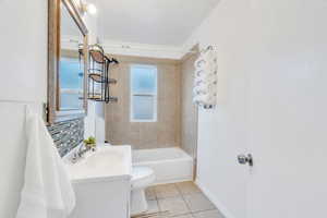 Bathroom featuring vanity, light tile patterned flooring,  shower combination, and decorative backsplash