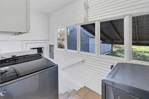 Washroom featuring independent washer and dryer, light tile patterned floors, and electric panel