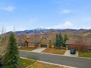 View of front facade featuring stone siding, a mountain view, driveway, and a garage