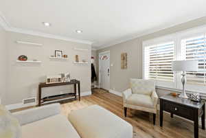 Living room featuring light wood-style floors, ornamental molding, and recessed lighting