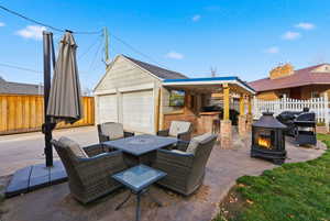 Fenced backyard with a patio area, outdoor dining space, a grill, an outdoor fire pit, and an outbuilding