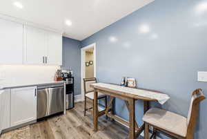 Kitchen with white cabinetry, dishwasher, decorative backsplash, light wood-style flooring, and recessed lighting