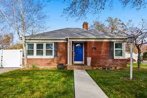 View of front of home featuring a gate, brick siding, and a chimney