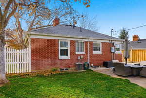 Back of property featuring outdoor lounge area, brick siding, a patio area, a chimney, and roof with shingles