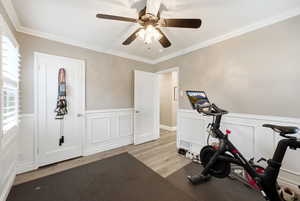Exercise room featuring wainscoting, a decorative wall, wood finished floors, and ceiling fan