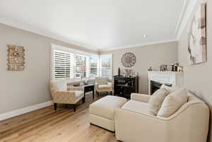 Living room with a fireplace, wood finished floors, and crown molding