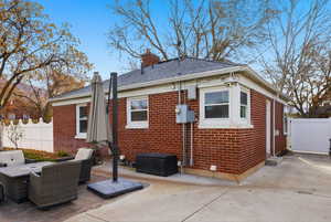 Back of property with a chimney, brick siding, and a patio