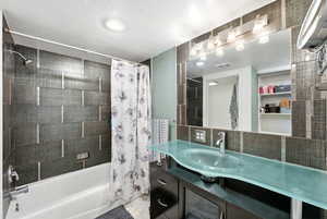 Bathroom with shower / bath combination with curtain and vanity