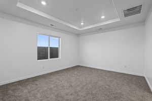 Carpeted spare room featuring recessed lighting and a tray ceiling