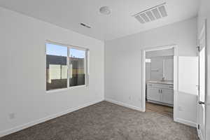 Unfurnished bedroom featuring dark colored carpet and ensuite bathroom