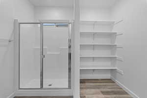 Full bath with a shower stall, light wood finished floors, and a closet
