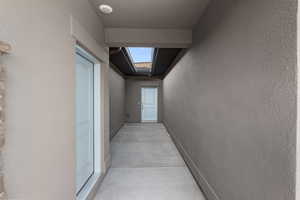 Hallway with a skylight, concrete floors, and a textured wall
