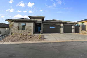 Prairie-style home featuring a tile roof, stucco siding, driveway, and an attached garage