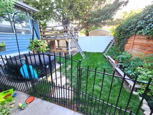 Fenced backyard featuring a vegetable garden and a pergola