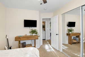 Bedroom featuring light carpet, ceiling fan, and washer / dryer