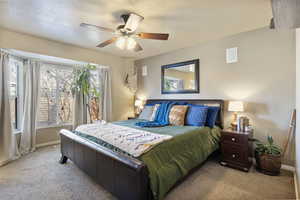 Bedroom with carpet floors, multiple windows, ceiling fan, and a textured ceiling