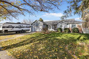 Ranch-style home featuring a front yard, an attached garage, and driveway