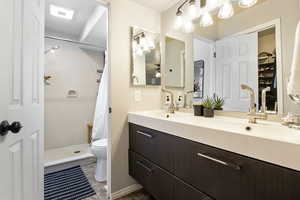 Full bath featuring double vanity, a stall shower, and a walk in closet