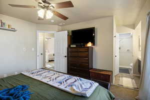Bedroom with ensuite bath, ceiling fan, and carpet flooring