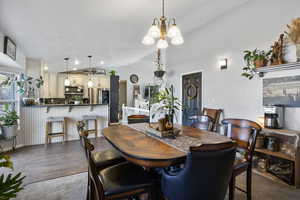 Dining space with vaulted ceiling, a chandelier, dark wood finished floors, and recessed lighting