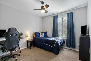 Carpeted bedroom featuring an office area and ceiling fan