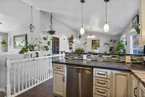 Kitchen with cream cabinets, plenty of natural light, backsplash, and vaulted ceiling