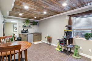 Kitchen with wood ceiling, open shelves, stainless steel refrigerator, light tile patterned flooring, and ornamental molding