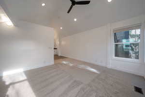 Spare room featuring lofted ceiling, ceiling fan, light colored carpet, and recessed lighting