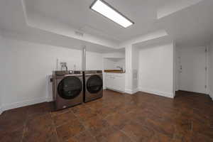 Laundry area featuring washer and dryer, cabinet space, and a tray ceiling