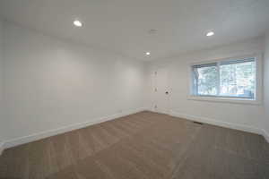 Carpeted spare room featuring baseboards and recessed lighting