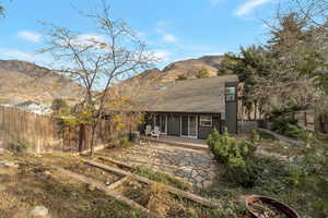 Rear view of house featuring a fenced backyard, a patio area, roof with shingles, a mountain view, and a sunroom
