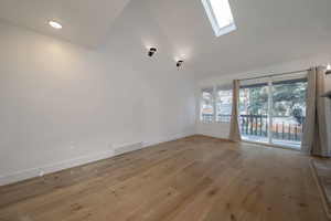 Unfurnished room with a skylight, light wood-type flooring, high vaulted ceiling, and recessed lighting